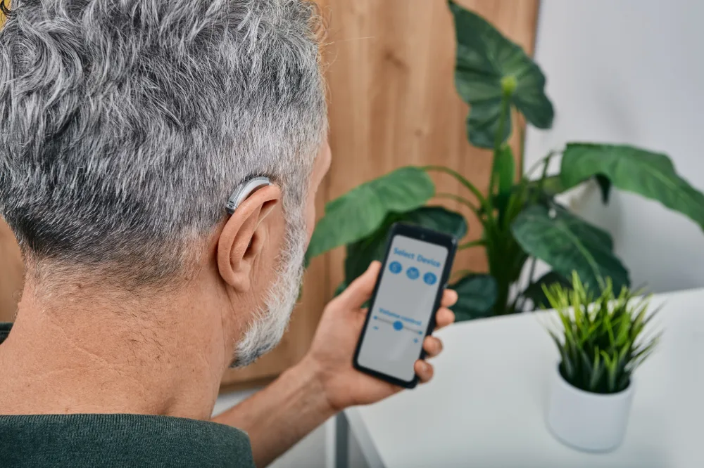 man with hearing aid holding paired iphone